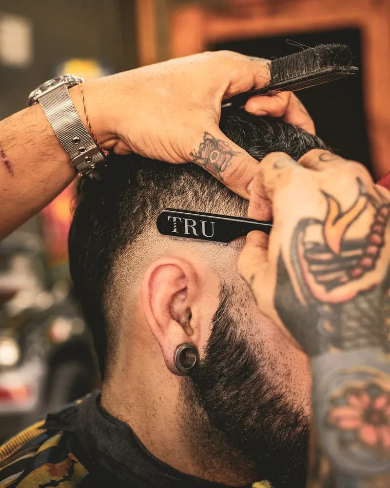 Barbero marcando con navaja una línea en el degradado de un cliente