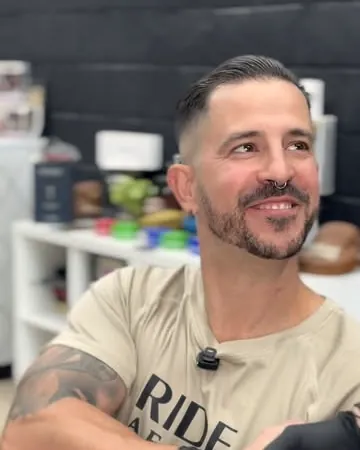 Cliente con barba sonriendo en el sillón al terminar el servicio