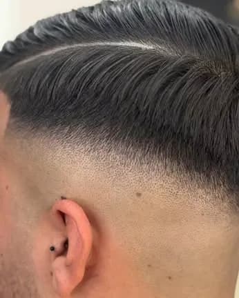 Nuca y lateral de un cliente con degradado a piel y raya lateral marcada a navaja